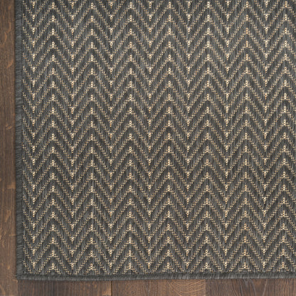 Charcoal and light gray herringbone rug with speckled yarn and dark border on wood floor.