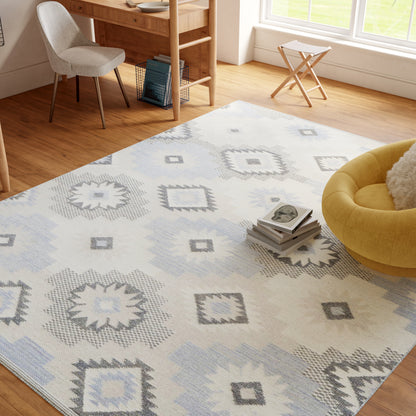 Rectangular woven area rug in white, pale blue and gray geometric diamonds; modern living room scene on hardwood floor.