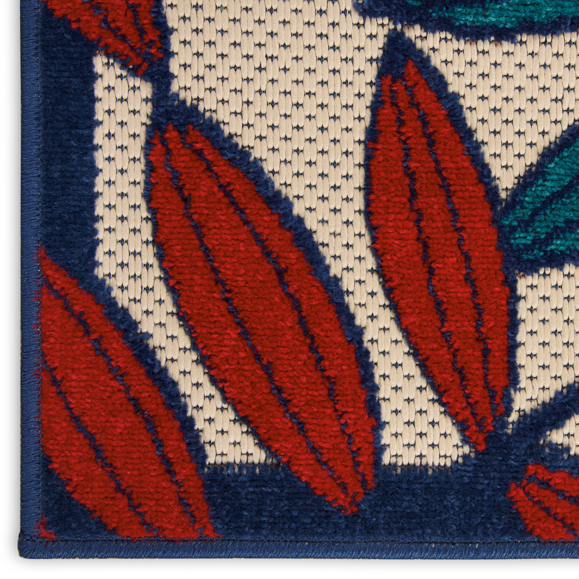 Close-up of a tufted rug with red leaf shapes outlined in navy on a beige background, blue border.
