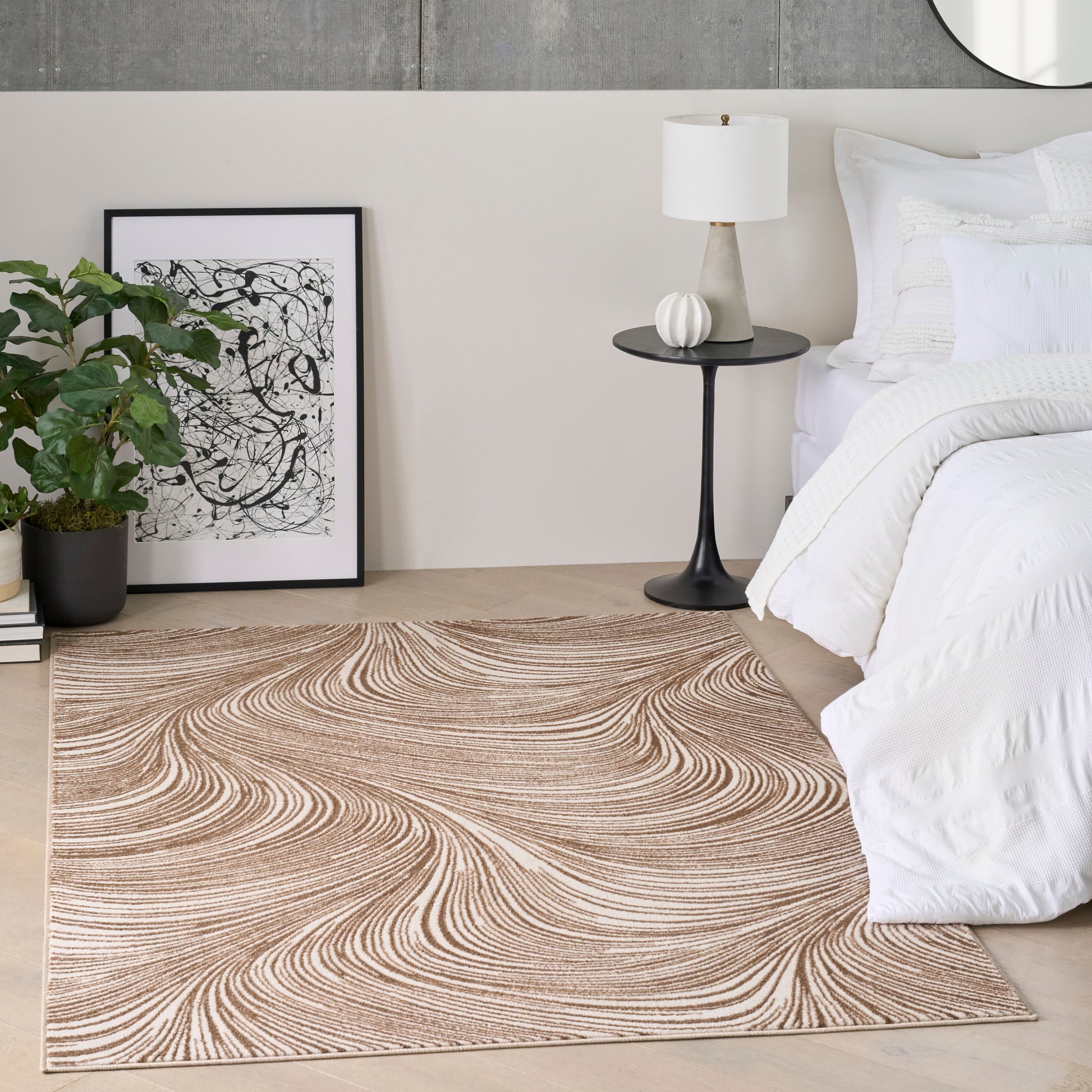 Rectangular beige woven rug with tan swirls on a light wood floor in a modern bedroom beside white bedding.