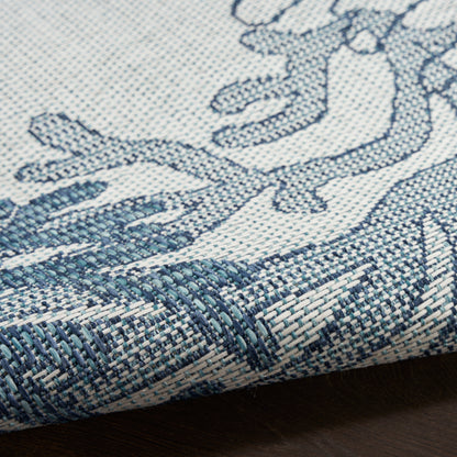 Blue and cream woven textile with coastal motif; textured jacquard rug edge visible.