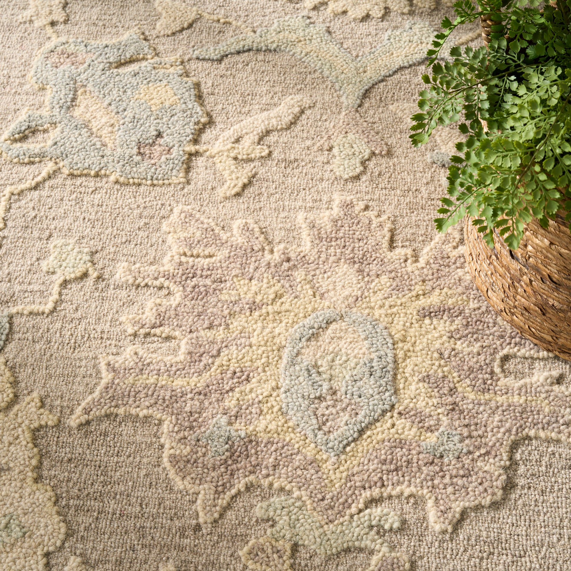 Pastel patterned rug in cream, pink, blue and yellow tones, with a woven basket and green plant in the upper right.