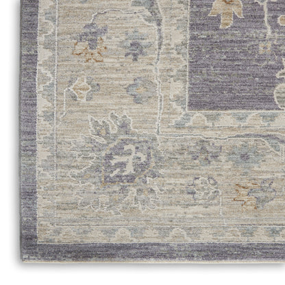 Rectangular vintage-inspired area rug in muted lavender, beige, ivory and gray with a floral border pattern.