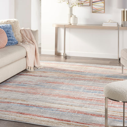 Cozy living room with a striped area rug in blues, grays and orange, a beige sofa, pink and blue cushions, and a minimalist console table.