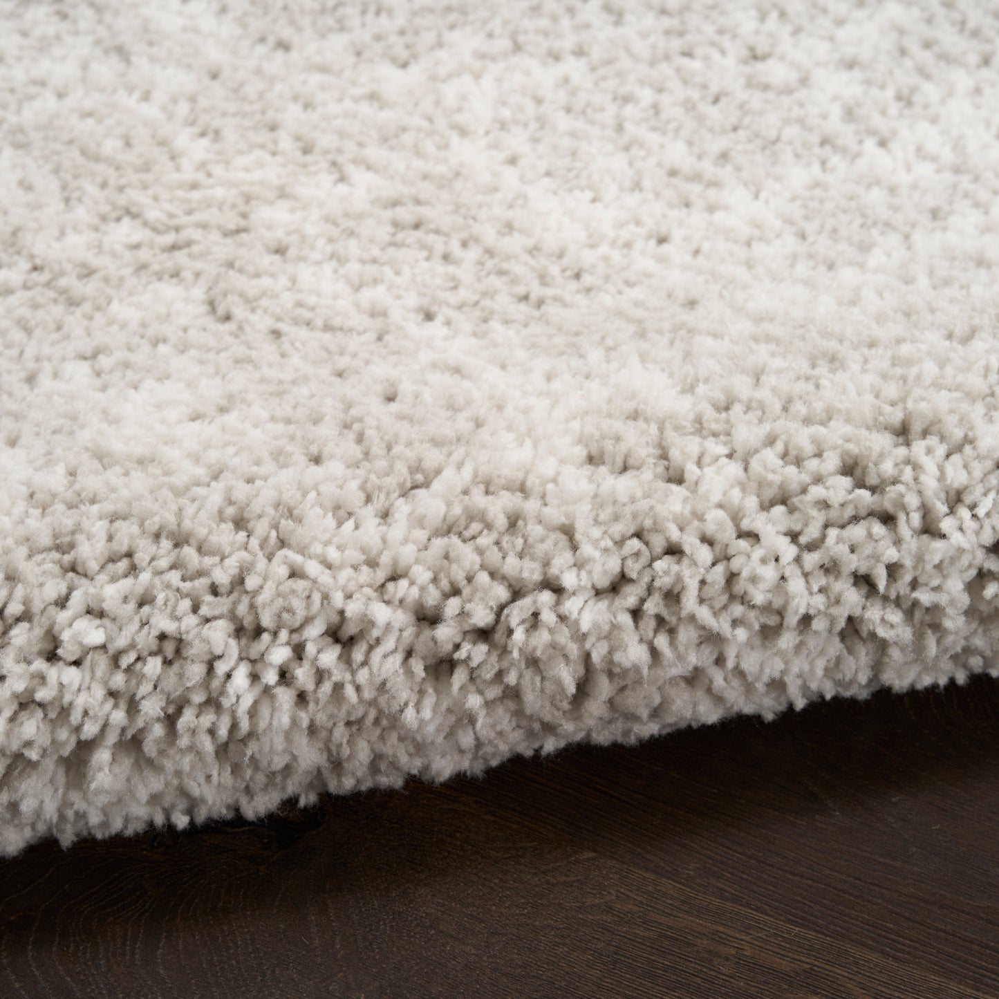 Cream shag rug with dense plush pile on dark wood flooring, cozy contemporary look.