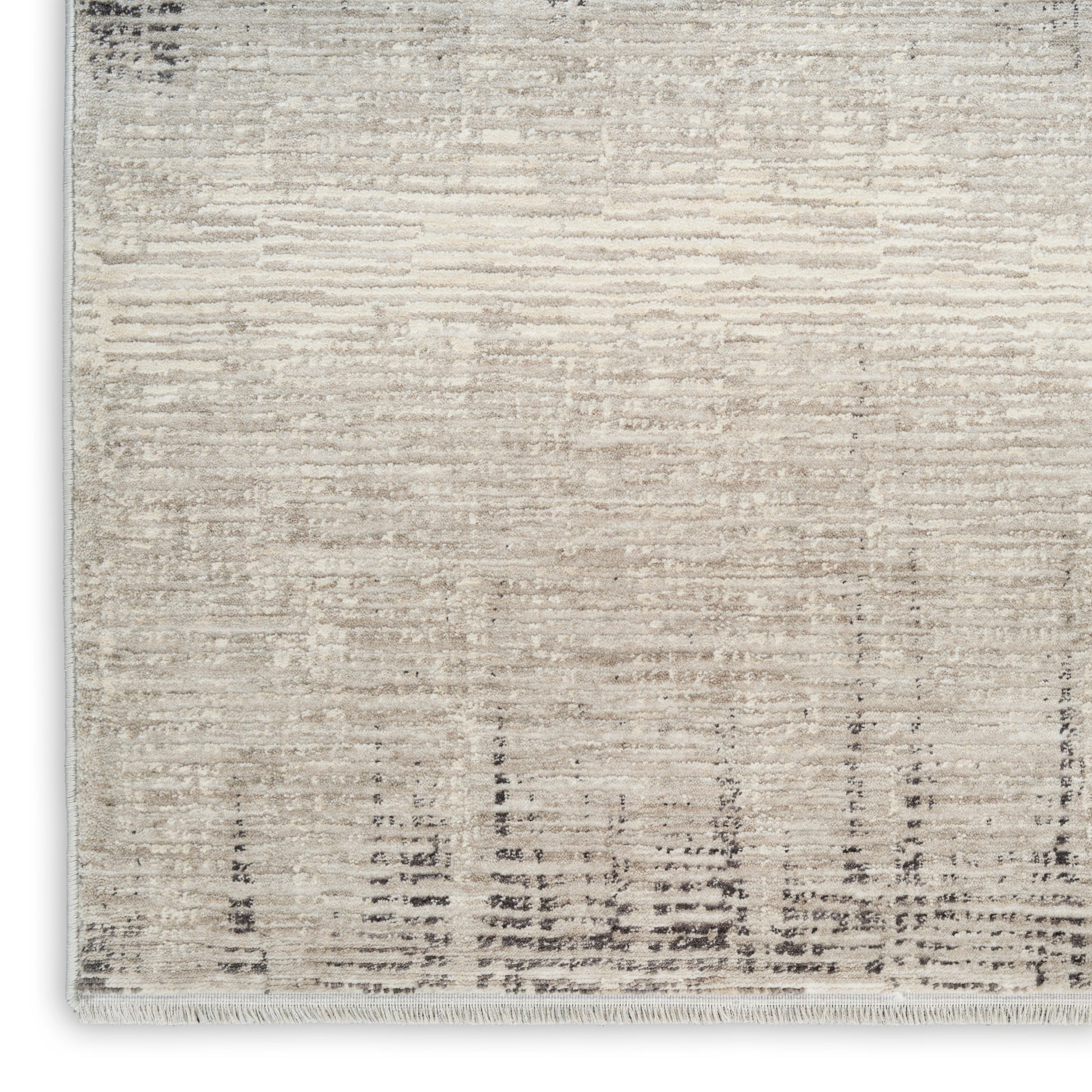 Beige and ivory distressed rug with subtle linear pattern and a fringed edge.