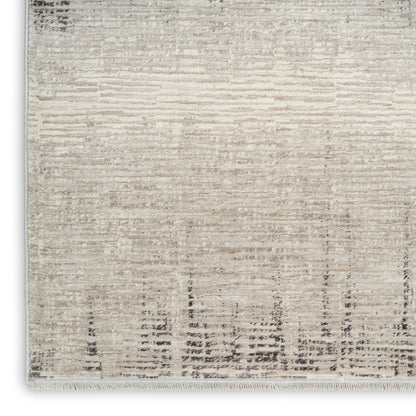 Beige and ivory distressed rug with subtle linear pattern and a fringed edge.