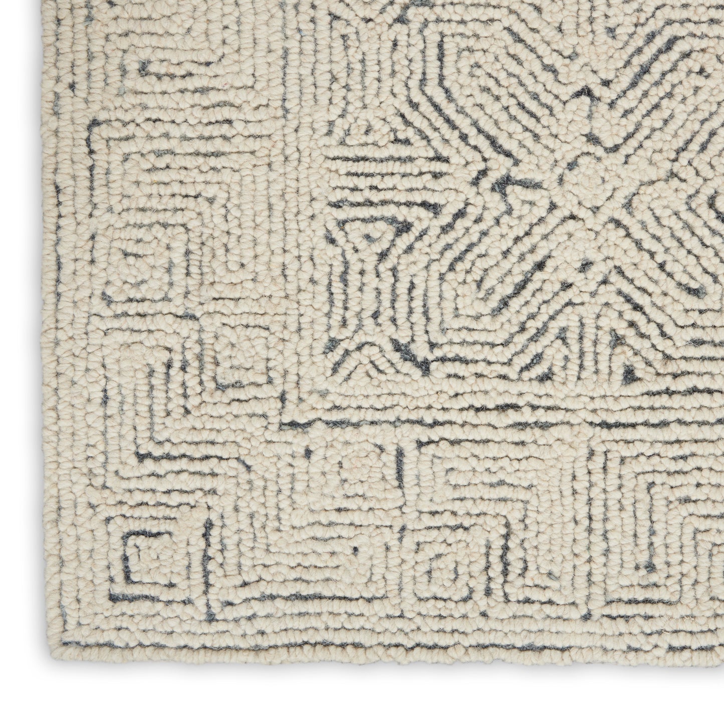 Cream shag rug with dark gray geometric maze pattern & soft tufted texture, corner edge visible.