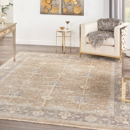 Neutral living room scene featuring a beige-gray patterned area rug (8' x 10'), cream armchair with gold legs, fur throw, and glass side table.