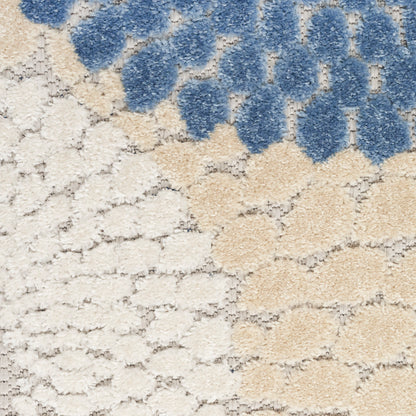 Close-up of a plush rug with cream base, tan honeycomb pattern, and blue tufted clusters along the top edge.