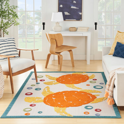 Coastal living room rug with orange crabs, teal border and colorful circles; light wood chairs and a white desk.