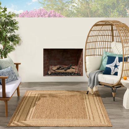 Beige woven rug (4' x 6') on an outdoor patio with a wicker egg chair and a potted plant.