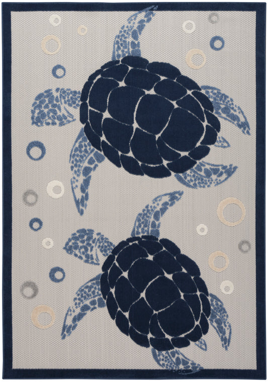 Rectangular woven area rug featuring two navy sea turtles on beige with light blue accent circles and a dark navy border.