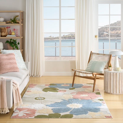 Pastel floral area rug in a coastal living room with light wood floor, white sofa, wicker chair, and sea-view windows.
