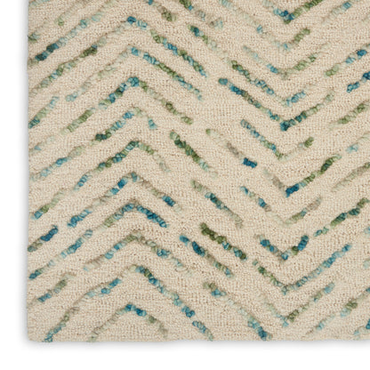 Cream textured rug with blue-green and teal chevron zigzags; looped boucle texture.