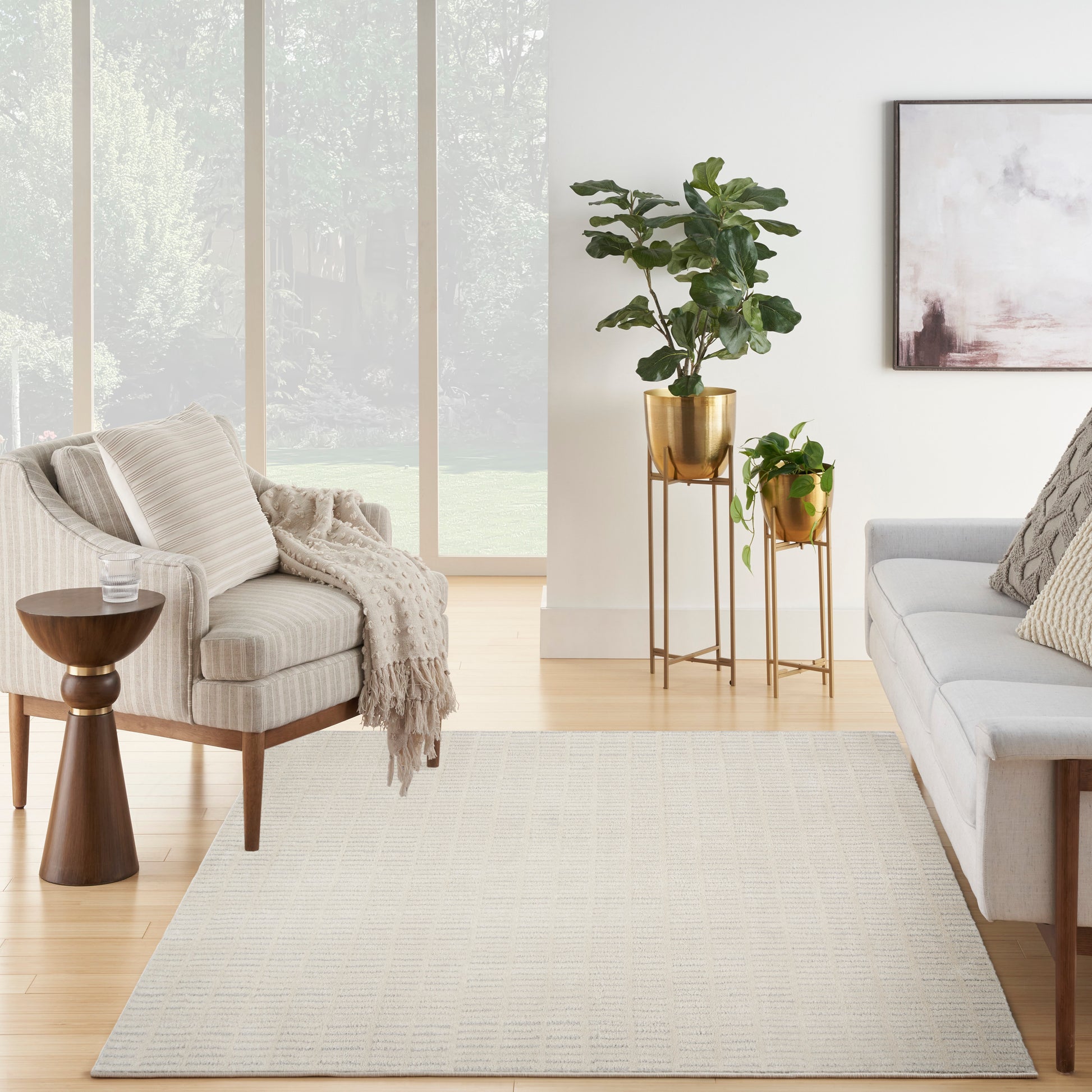 Neutral Scandinavian living room featuring a beige armchair, light gray sofa, a textured rug (8' x 10'), and gold plant stands with greenery.
