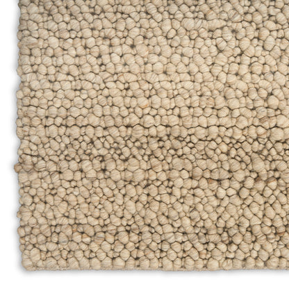 Beige textured loop-pile rug close-up; tight rounded tufts in neutral cream for living room decor.
