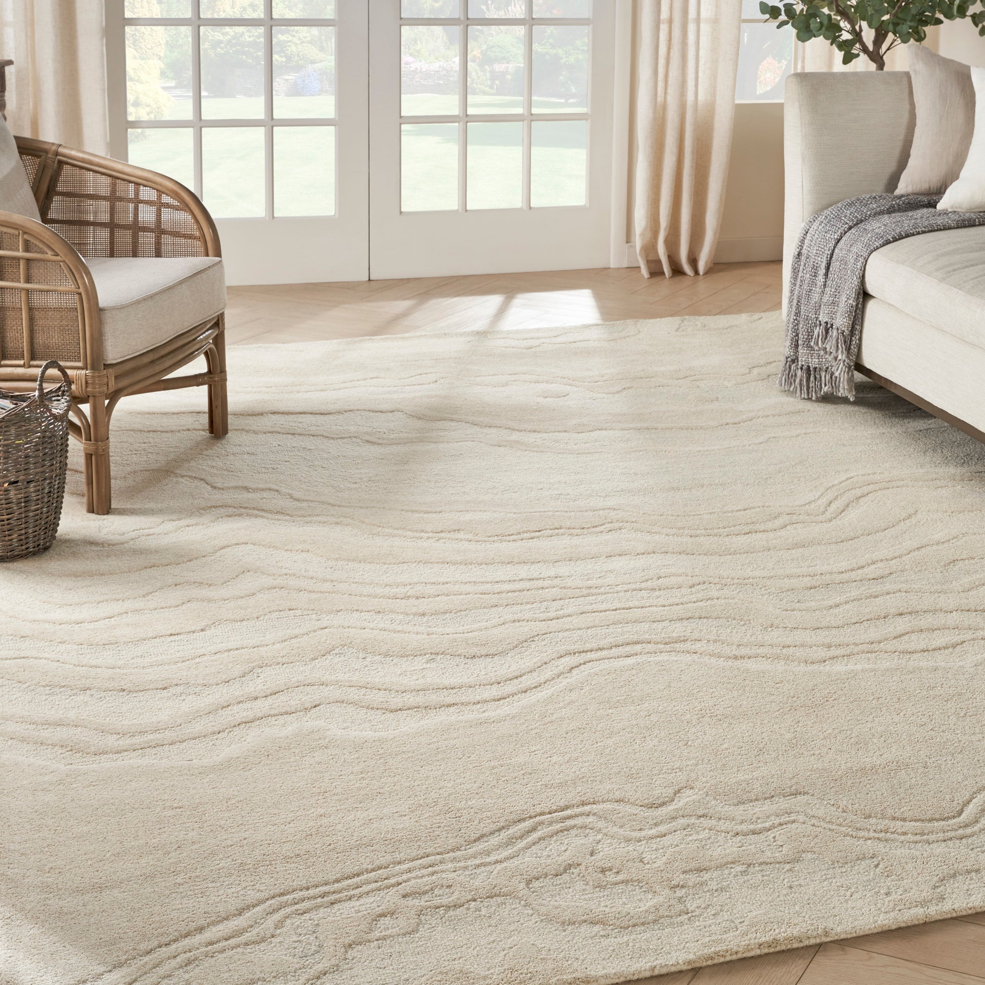 Cream-beige area rug with subtle wavy pattern and woven texture in a bright living room.