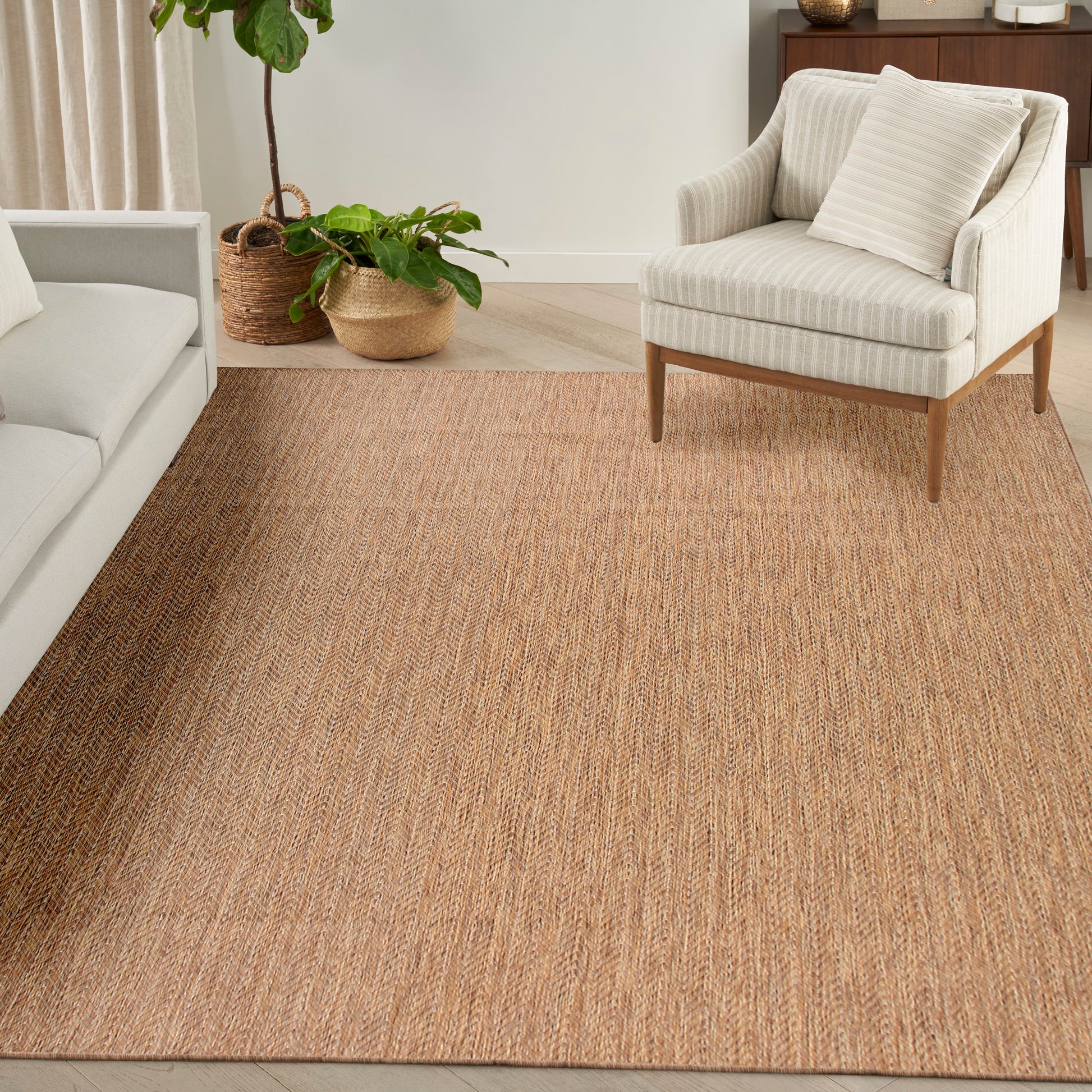 Beige natural jute rug with woven texture in a contemporary living room with cream sofa and striped armchair