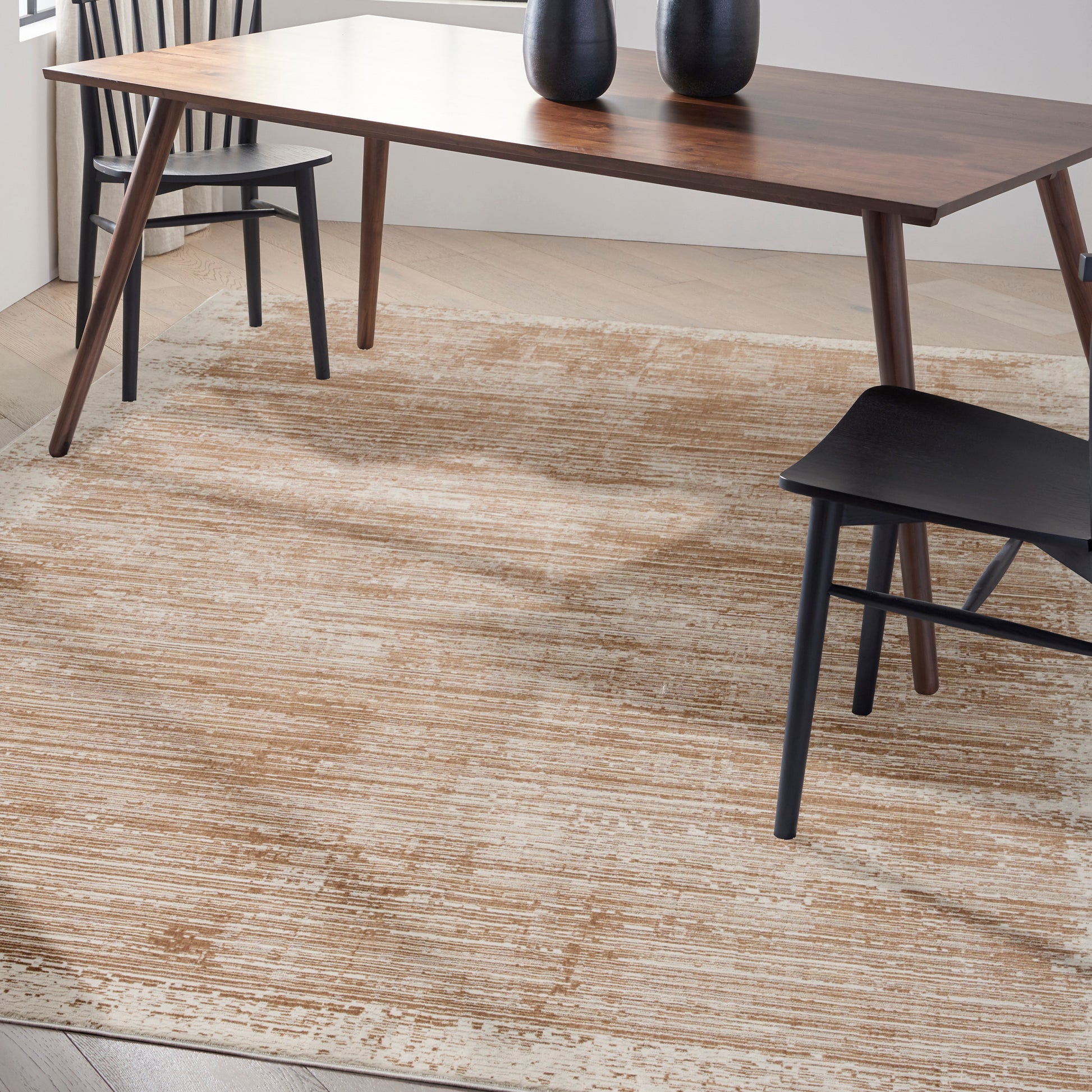 Mid-century dark walnut dining table with tapered legs, two black vases, and black and wooden chairs on a beige textured rug.