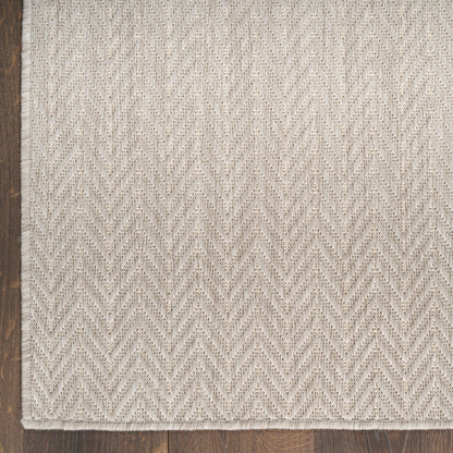 Cream-beige chevron-pattern flatweave rug with textured weave on wood floor; neutral area rug.