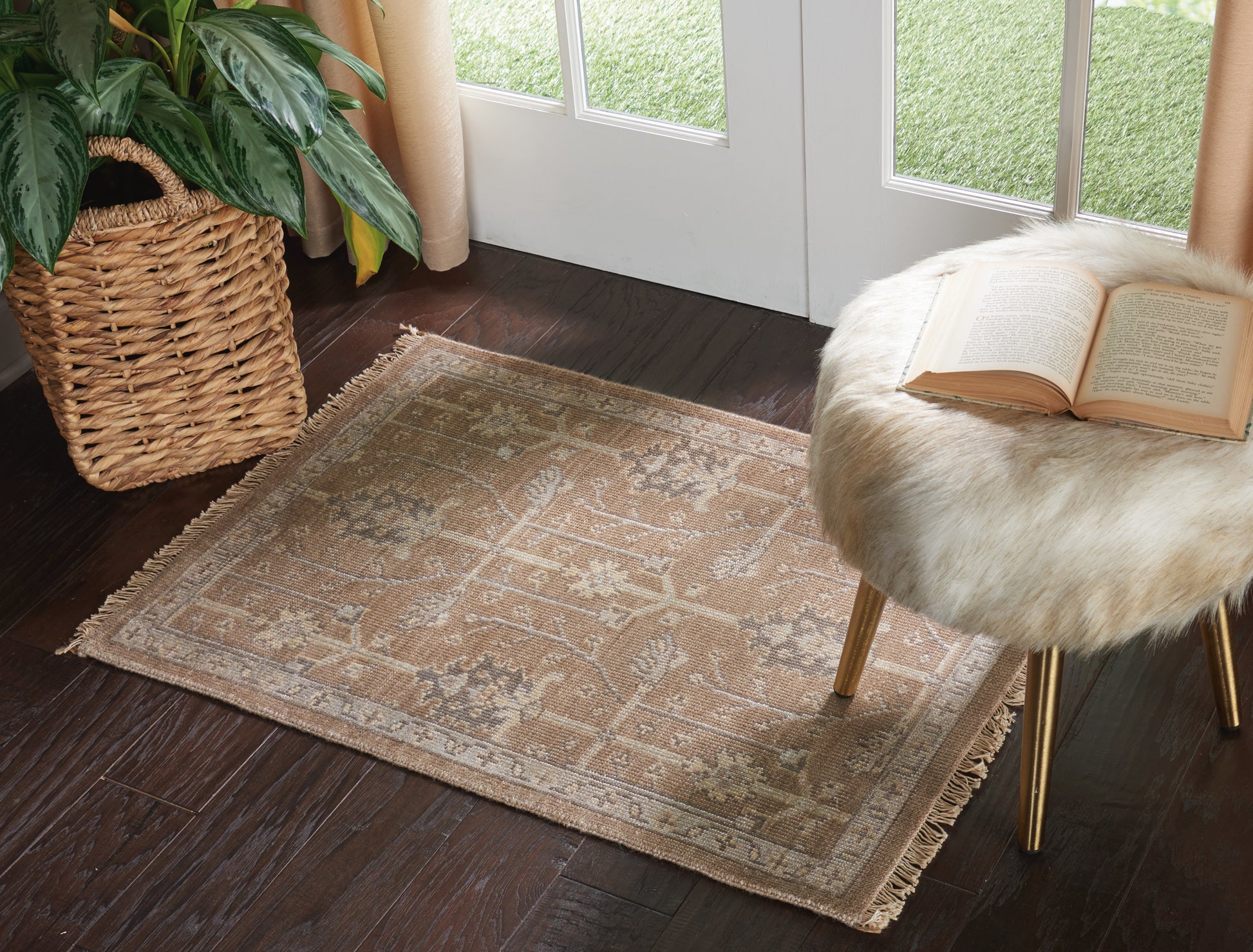 Beige oriental area rug with fringe on dark wood floor beside a fur-covered stool and open book.