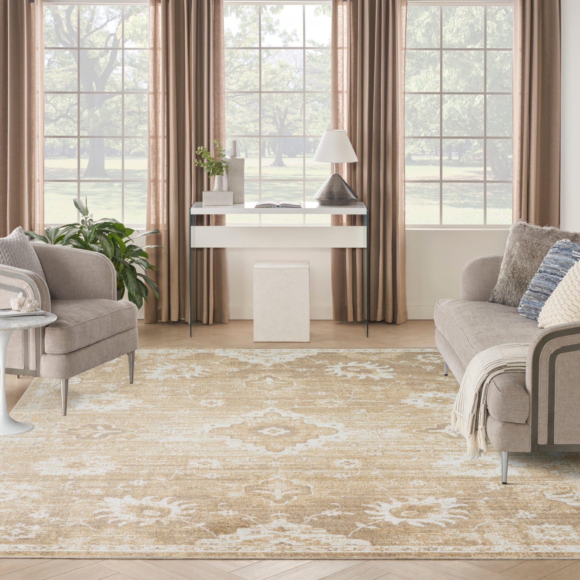 Bright living room with beige curtains, two grey sofas, ornate beige rug, white console table with plant and lamp.