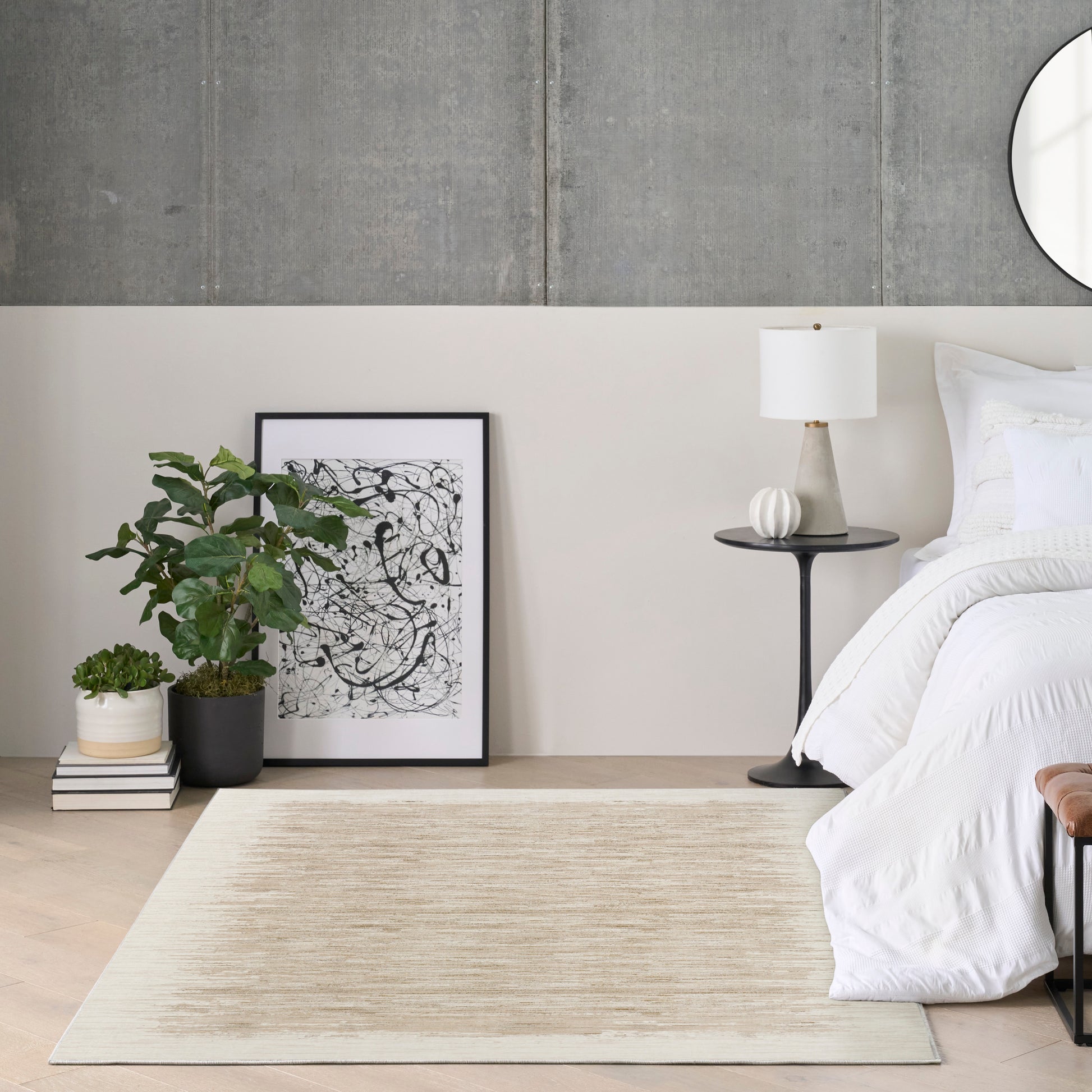 Modern bedroom corner with white bedding, black nightstand & lamp, beige rug, leaning abstract line art, potted plant.