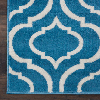 Blue and white Moroccan-trellis rug on dark wood floor.