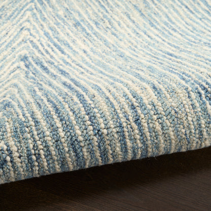 Blue and ivory loop-pile rug with subtle striped gradient and plush texture on dark wood floor.