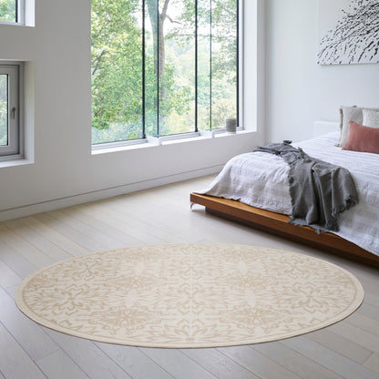 Beige round rug with a subtle pattern in a bright modern bedroom with a low wooden bed and white linens.