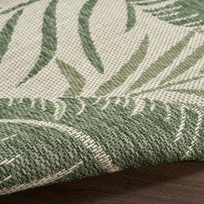 Close-up of green and cream woven rug with palm leaf pattern, textured yarns, folded edge over dark wood.