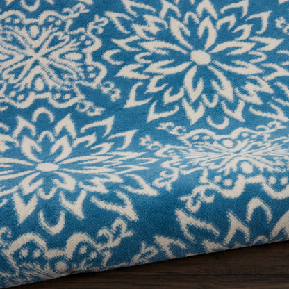 Blue fabric with white mandala floral pattern, soft textile, folded edge, decorative throw or blanket.