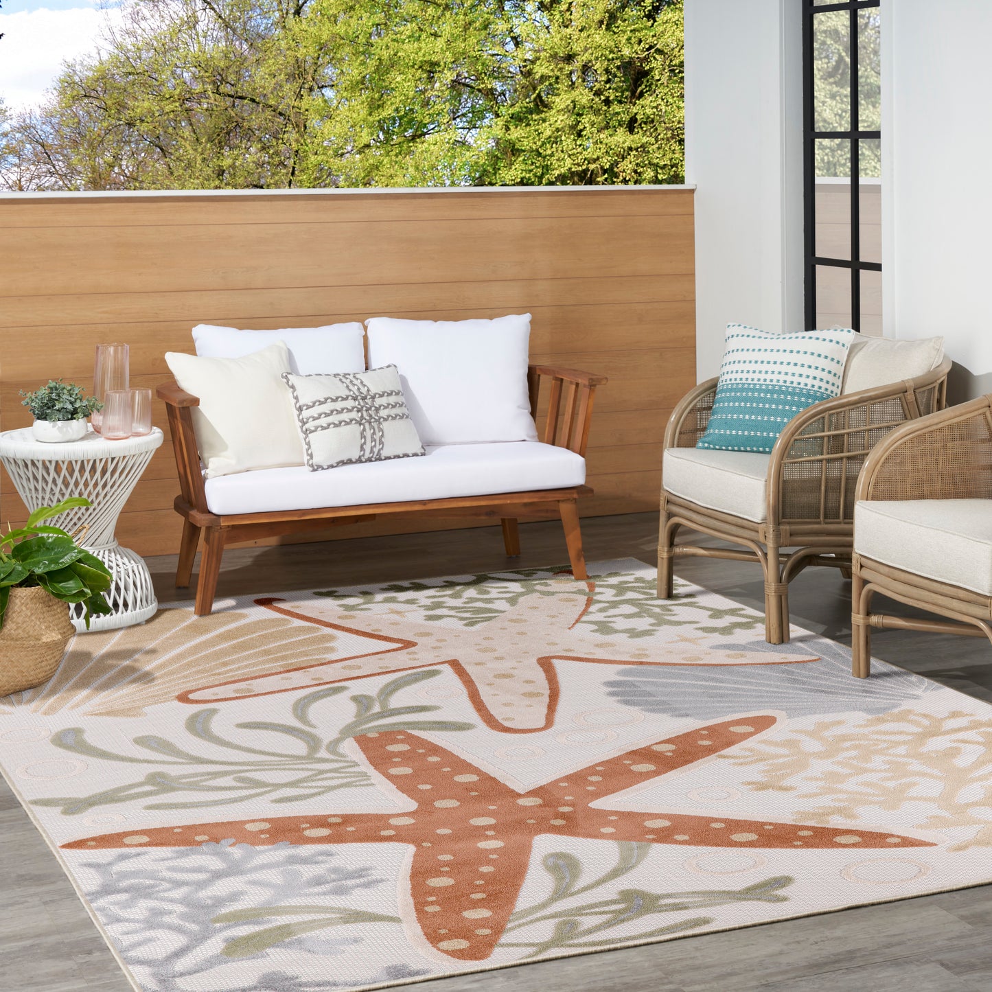 Outdoor rug with a starfish-pattern in orange and beige, 9' x 12', on a patio.