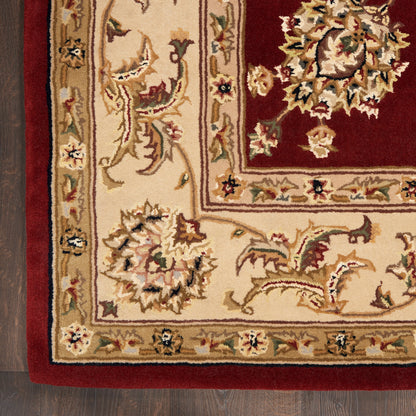 Persian-style area rug with cream field, red central panel and intricate floral motifs; beige and maroon palette; wood floor visible.