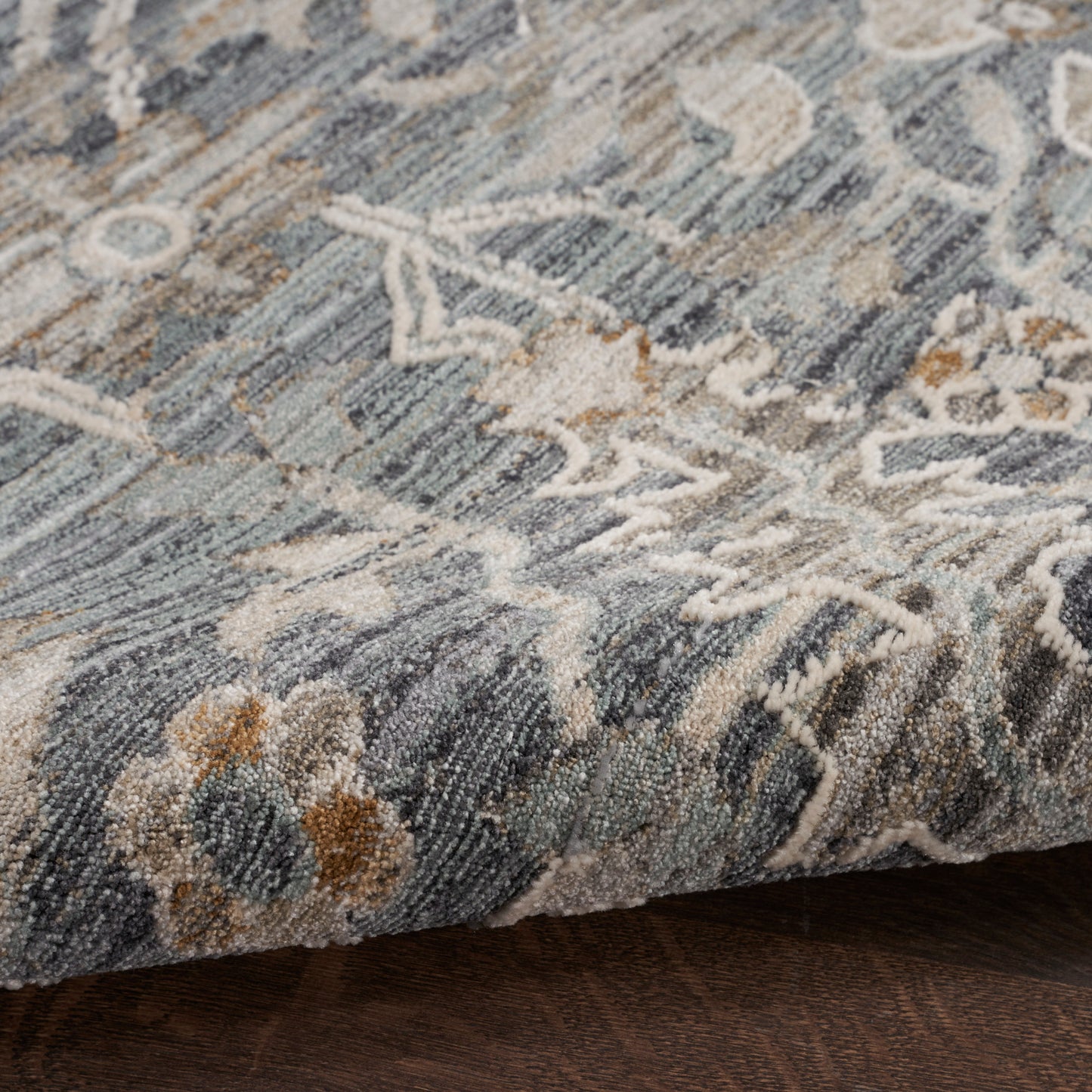 Blue-gray floral patterned rug with cream and tan accents, textured woven pile.