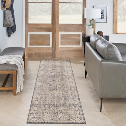 Neutral distressed runner rug in a cozy living room entry with gray leather sofa, wooden doors, & a bench with throw.