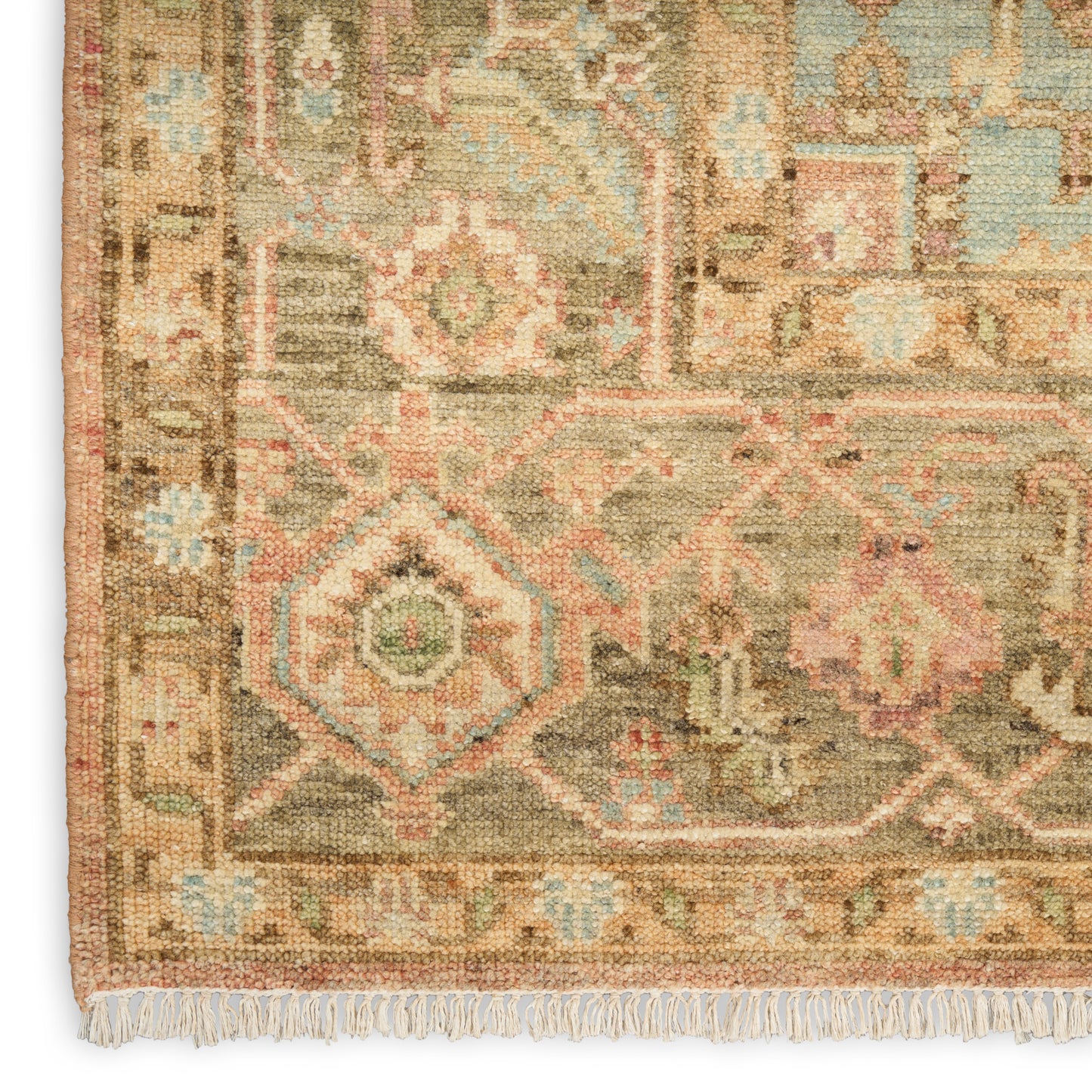 Geometric Persian-style rug corner with beige base, pink, blue and green motifs, fringed edge.