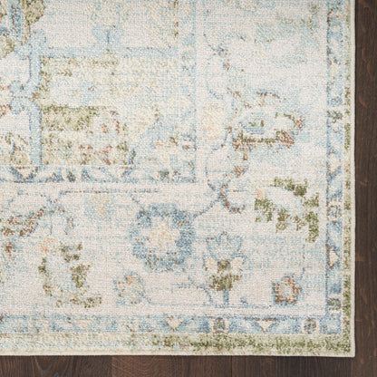 Pastel blue, ivory and sage green vintage-style floral area rug on dark wooden floor