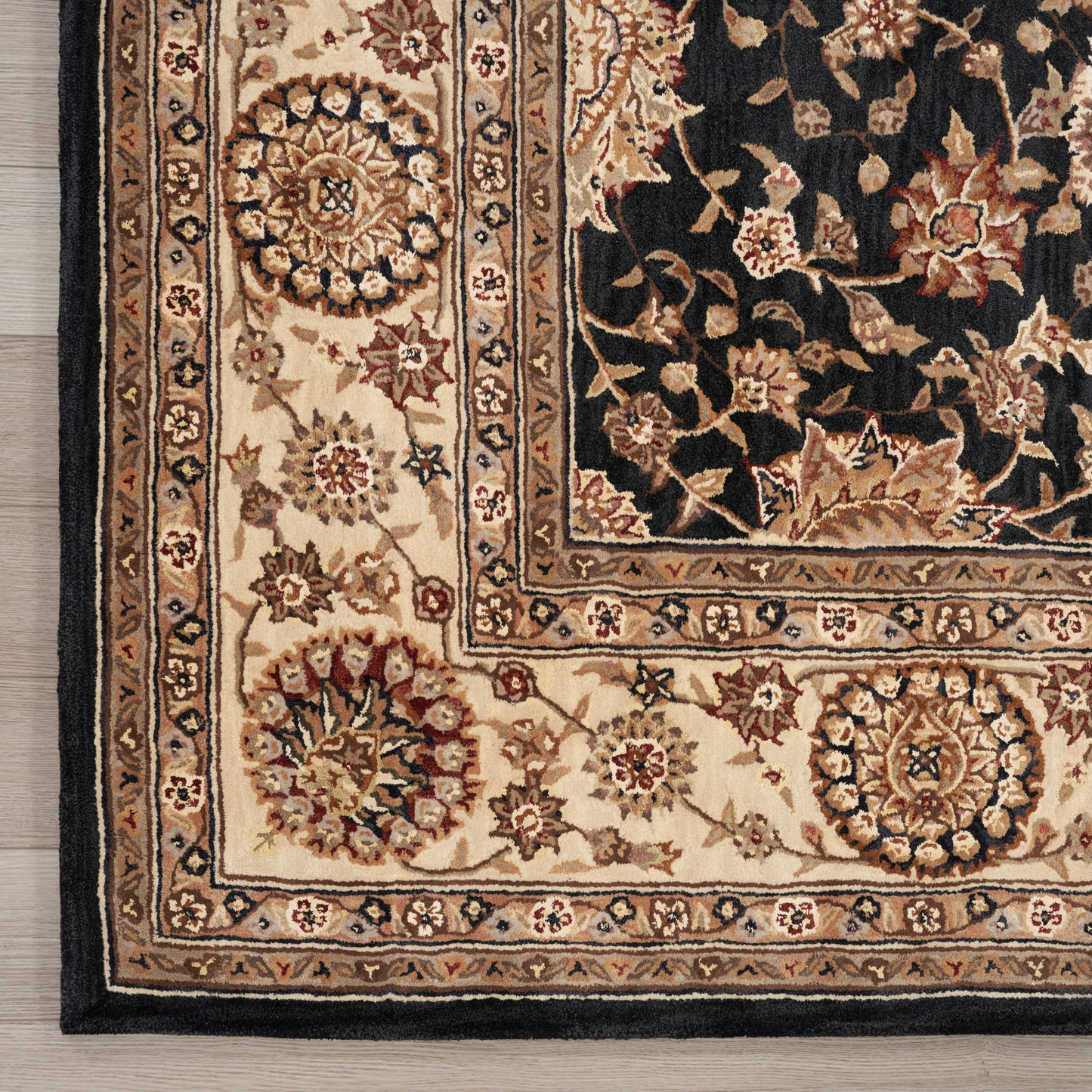 Traditional Persian-style rug corner with cream/beige borders featuring medallions and a black field with tan floral vines.