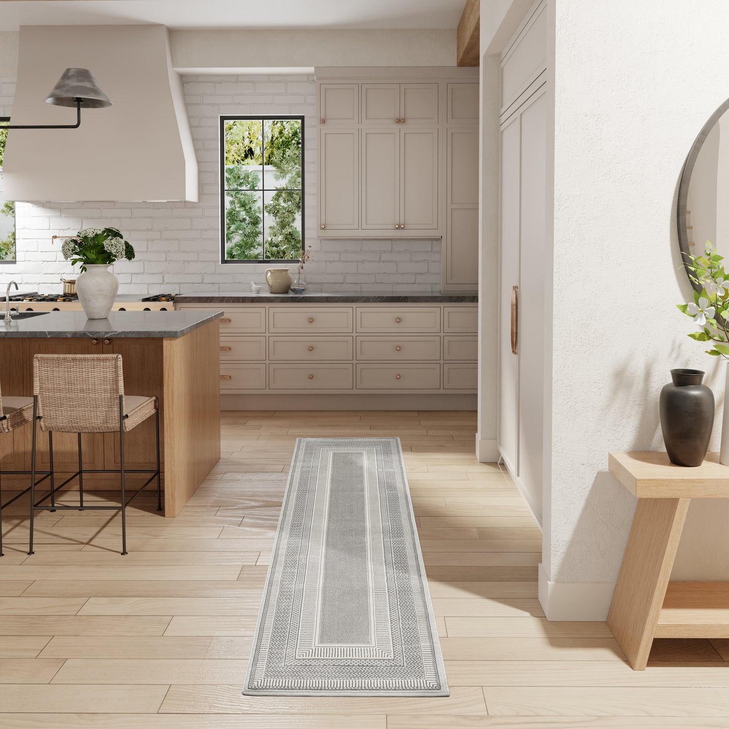 Bright kitchen with white cabinets, wood island, light wood floors, gray geometric runner rug, window & potted plants.