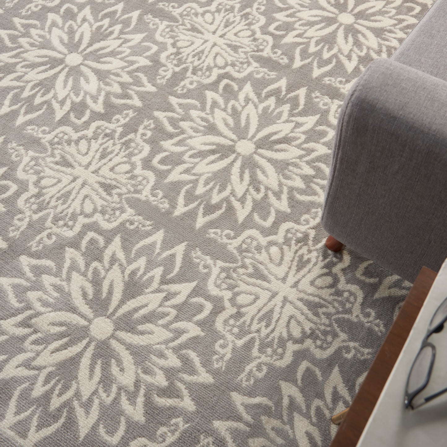 Grey area rug with bold white floral medallion pattern; plush texture for a modern living room with a gray sofa.