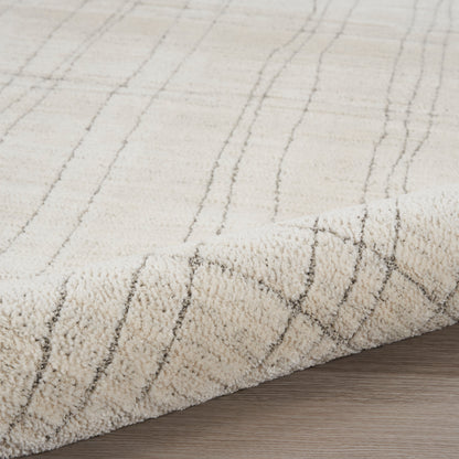 Beige plush area rug with subtle gray diagonal grid lines, rolled edge on wood floor.