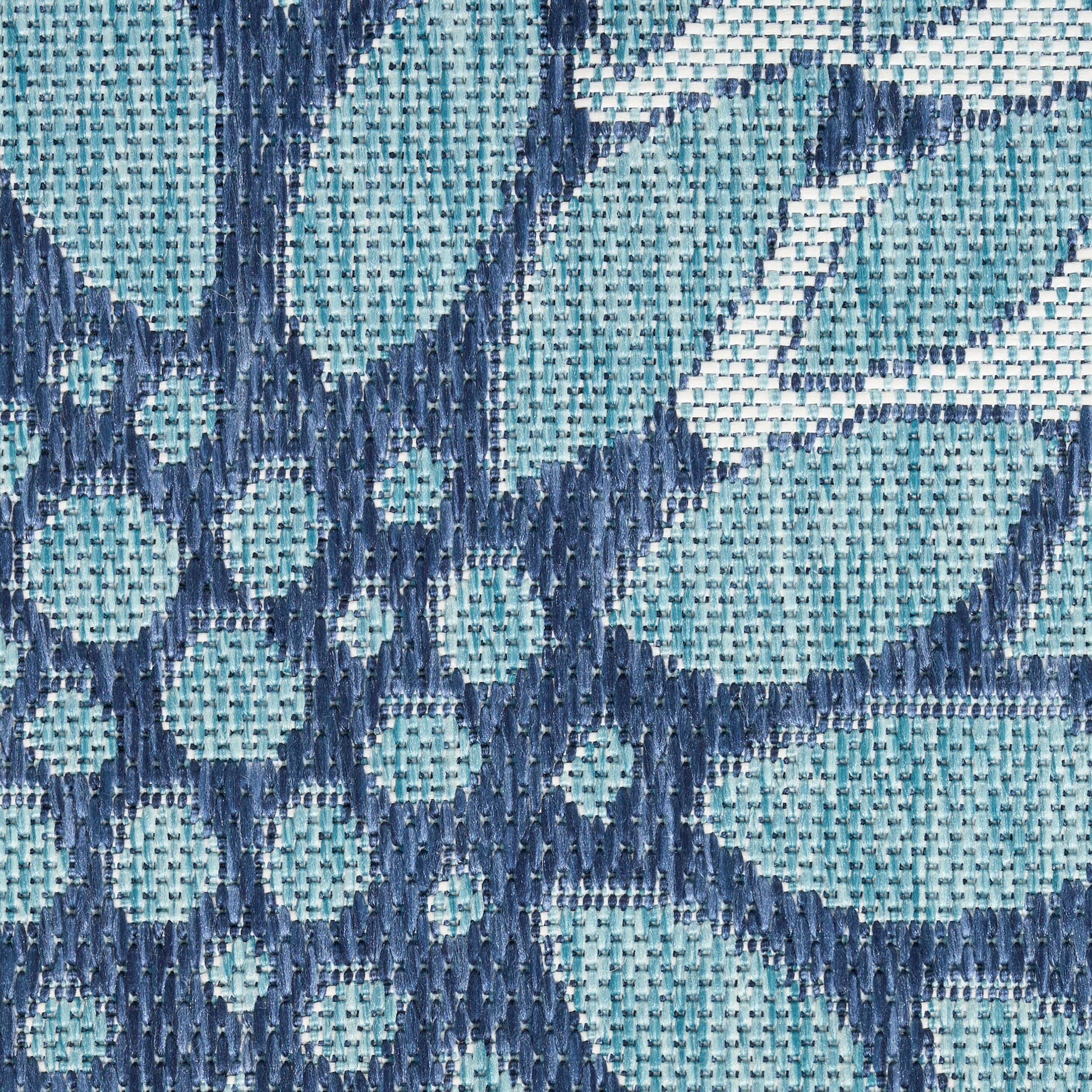 Close-up of teal and navy geometric woven rug with diamond and circle patterns.