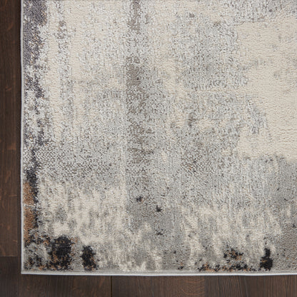Rectangular abstract distressed area rug in ivory, gray and black on dark wood floor; soft pile.