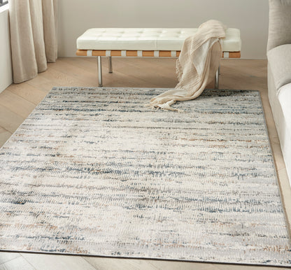 Cream tufted bench with wooden slats and metal legs, draped beige throw, on a gray-blue abstract rug in a bright living room.