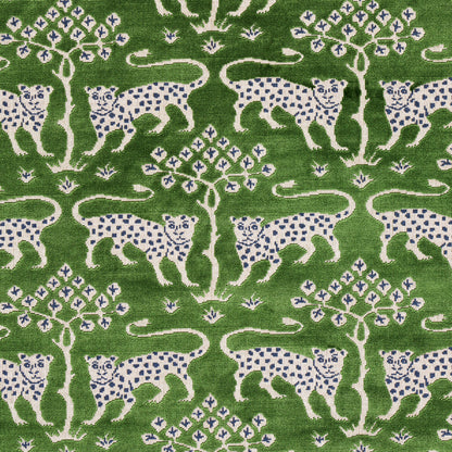 Green fabric featuring white leopards with blue spots and stylized trees in a repeating nature motif.