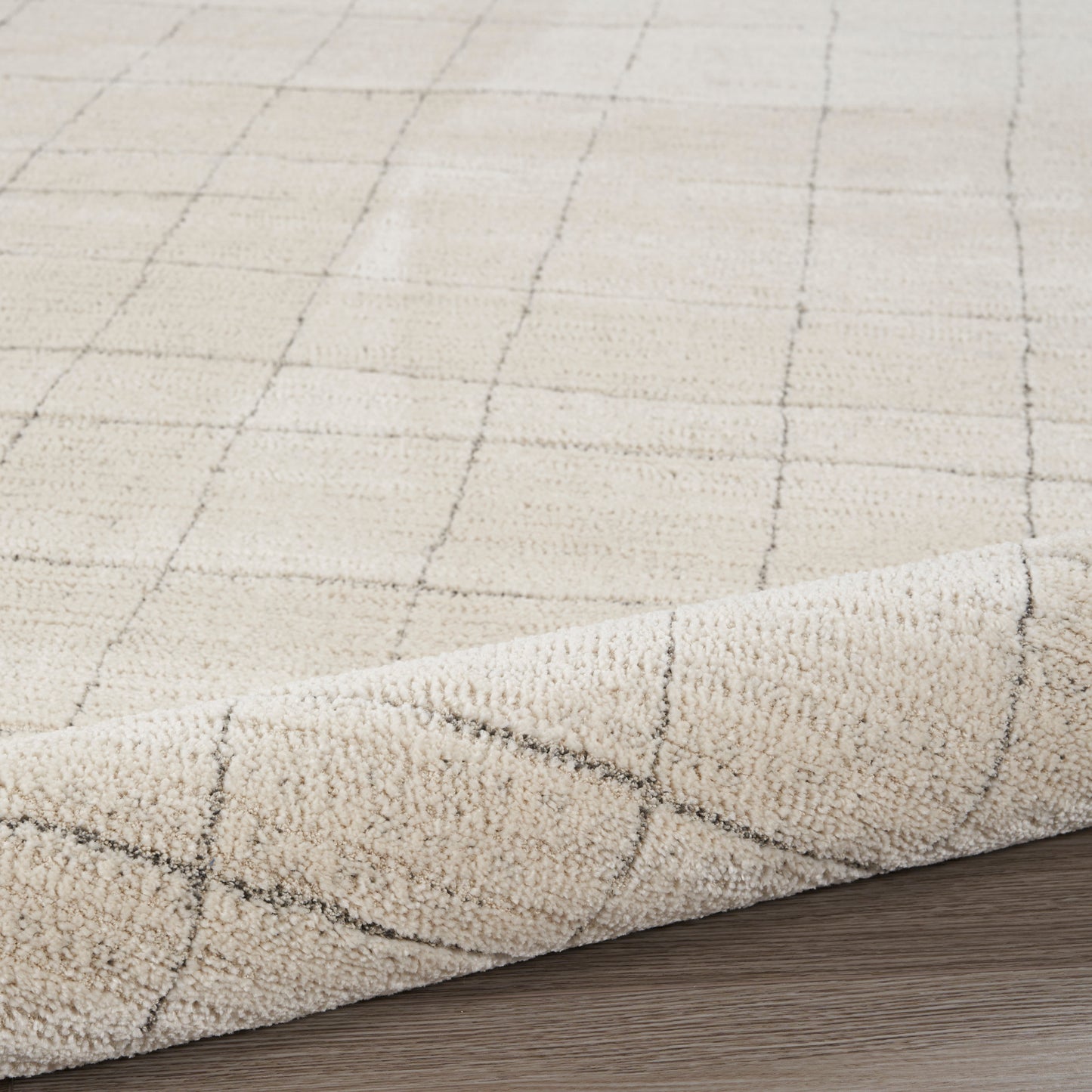 Beige 8' runner rug with a subtle dark grid pattern and soft pile, curled edge on wood floor.