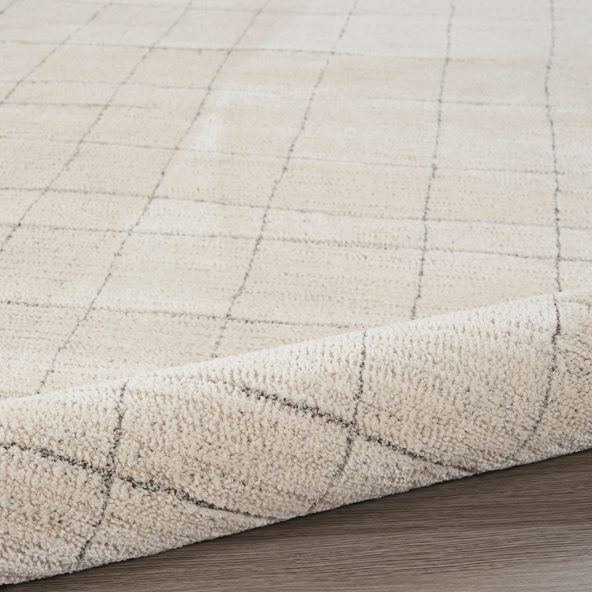 Beige 8' runner rug with a subtle dark grid pattern and soft pile, curled edge on wood floor.