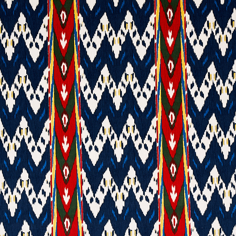 Ikat-inspired navy and white textile with bold red vertical stripes and green diamond accents; versatile fabric.